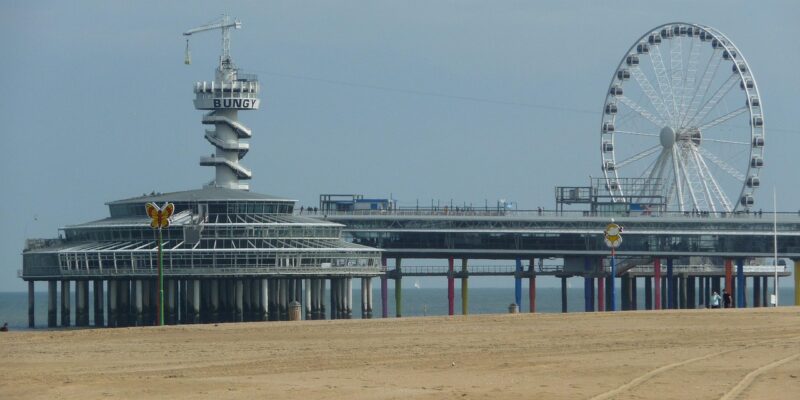 Scheveningen-Pier: Bungy-Tower & Riesenrad Tagesansicht der Pier von Scheveningen mit dem markanten Bungy-Tower, dem SkyView-Riesenrad und den bunten Stützpfeilern, davor der weite Sandstrand bei ruhiger Brandung