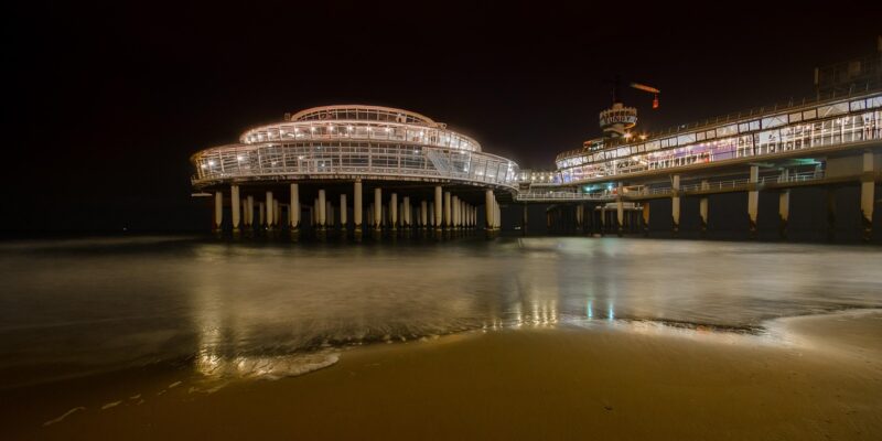 Nacht, Beleuchtung & Bungy-Tower Die Pier von Scheveningen bei Nacht mit beleuchtetem Pavillon, dem Bungy-Tower und Lichtreflexen auf dem nassen Sandstrand und ruhigem Meer