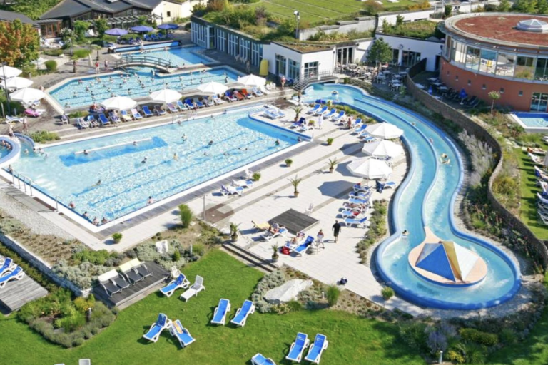 Außenbecken und Strömungskanal der Chiemgau Thermen Luftaufnahme der Außenanlage mit mehreren Thermalbecken, Strömungskanal, Liegen und begrünten Ruheflächen