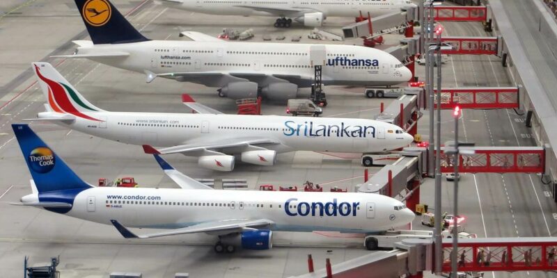 Miniatur Wunderland Eine Miniatur-Flughafenszene, die im Miniatur Wunderland aufgenommen wurde, zeigt Modellflugzeuge von Fluggesellschaften wie Condor, SriLankan und Lufthansa. Diese Flugzeuge parken an Gates mit angeschlossenen Fluggastbrücken, während kleine Bodendienstfahrzeuge auf dem Rollfeld manövrieren.