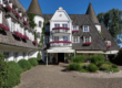 Weiße Hotelfassade mit Türmen, Blumenschmuck und rundem Vorplatz