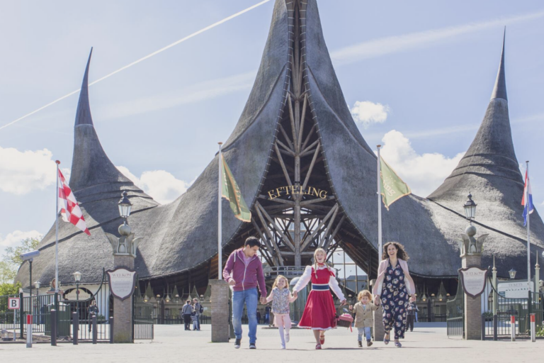 Haus der fünf Sinne – Eingang von Efteling Familie läuft vor dem markanten reetgedeckten Haupteingang Haus der fünf Sinne