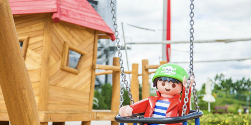 Pirat auf der Schaukel im Playmobil FunPark Playmobil-Pirat auf einer Schaukel vor einem Holzspielhaus im Playmobil FunPark