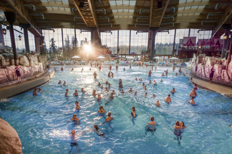 Großes Wellenbecken Surf Fjørd mit Badegästen, Felsenlandschaft und nordisch gestalteten Gebäuden
