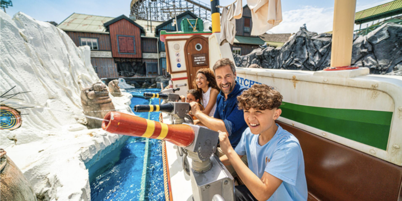 Eine fröhliche Familie sitzt in einem skandinavisch gestalteten Boot im Europa-Park und zielt mit installierten Wasserkanonen auf Ziele in einer künstlichen Eislandschaft mit Walross-Figuren.