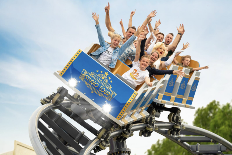 Movie Park Studio Tour in voller Fahrt Fahrgäste mit erhobenen Armen in der blauen Achterbahn der Movie Park Studio Tour