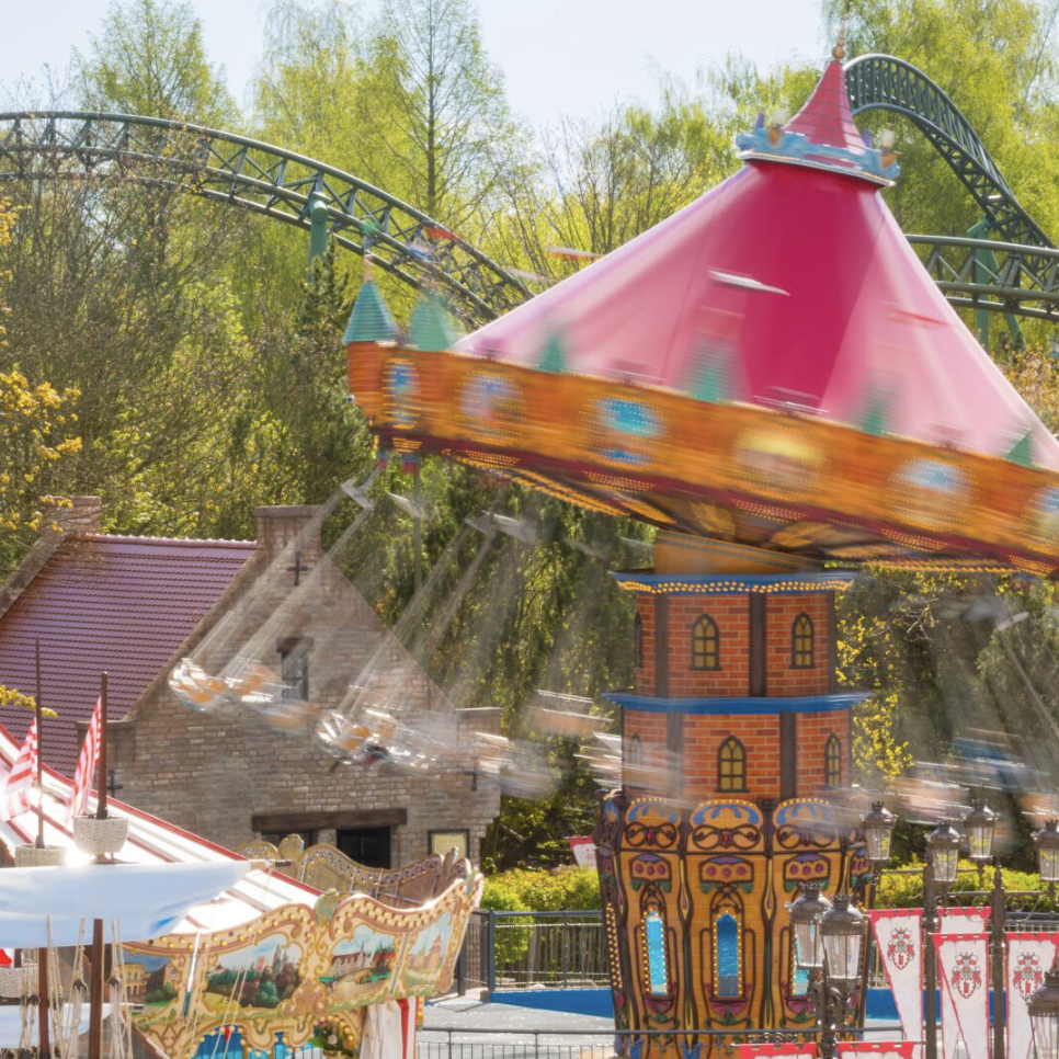 HANSE-Flieger mit buntem Dach und Achterbahn im Hintergrund im HANSA-PARK